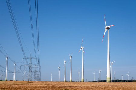 Electricity pylons with power lines and wind energy plants.