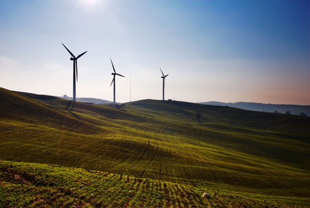 Three wind turbines silhouettes on top of hillの写真素材