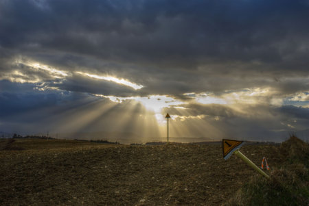 Hdr immage: sun beams bursting through very dark threatening clouds over the methane tubes sign posts(metanodotto is not a trademark, it just means methane tubes)の写真素材