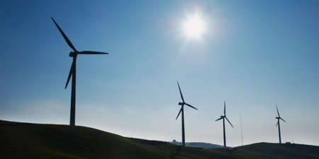 Four wind turbines silhouettes on top of hillの写真素材