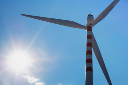 Modern and ecologic wind turbine silhuette beside the bright sun