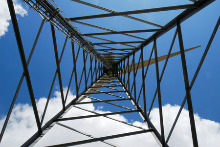 Wind turbine trellis viewed from bottom against blue and white sky