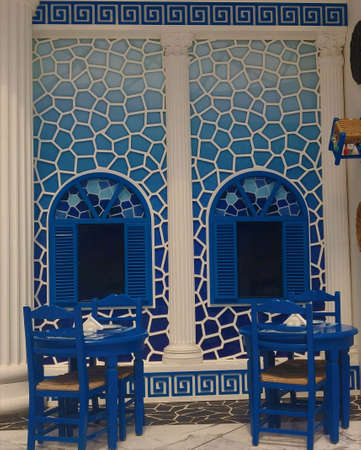 Ancient window with blue artwork and blue coffee table with blue chairsの写真素材