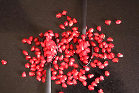 October 2020 at Mumbai.  Pomegranate seeds scattered on a black platter with two spoonsの写真素材