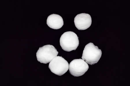 Cotton ball smiley face isolated on black.の写真素材
