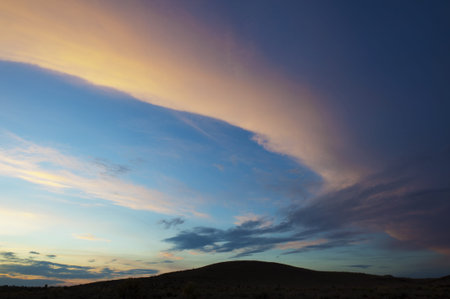 A small hill silhouetted against a beautiful sunset sky.の写真素材