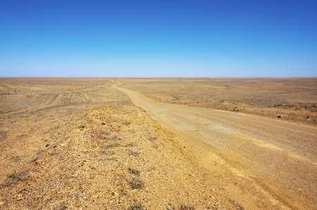 A long dirt road leads further into the arid desert.の写真素材