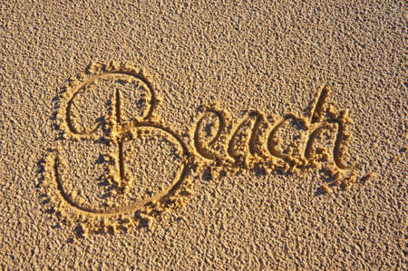 The word 'Beach' hand written in the sand. Summer vacation concept.の写真素材