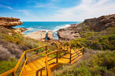 Wooden staircase leading down to a rugged, untouched coastline.の写真素材