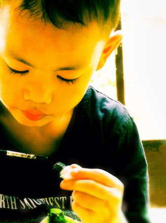 A boy put paint on a brushの素材