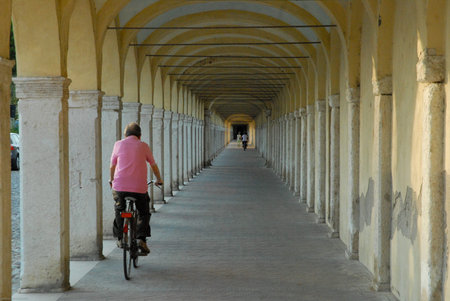 image of the old arcades of Comacchio with people who cycle, also it means go ahead, although with difficulty, and reach instillの写真素材