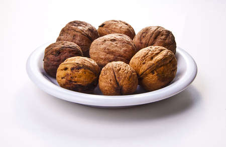 Walnuts on white plate, isolated on a white backgroundの写真素材