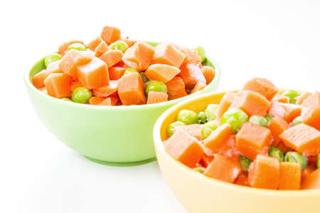 Close-up of a frozen vegetables mix in colorful kitchen bowls isolated on white の写真素材
