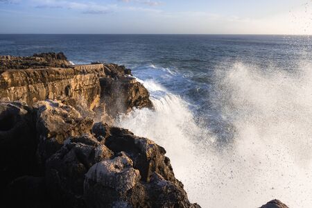 sunset on the coast. waves crash on the rock. Cascais Portugalの写真素材