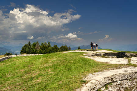 Tourists admire the landscape from the top of Cima Campo, ArsiÃ¨, Belluno. Green meadow and trees on cloud covered skyのeditorial素材
