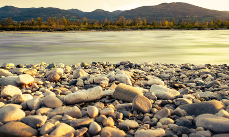 Landscape from the rocky banks of the Piave River at sunset. Silky flowing waters. In the background...