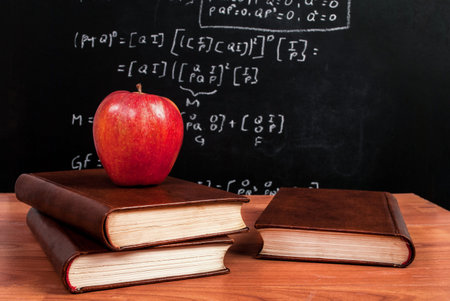 Apple on books on a wooden desk during math class in the classroom