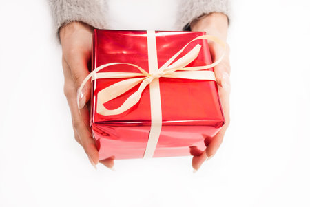 Female hand holding red box present with white bow