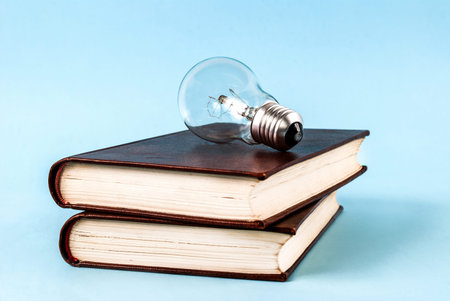 Bulb on two closed books isolated on a blue background