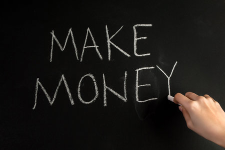 Girl hand write word Make Money with white chalk on blackboard
