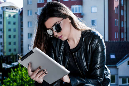 Beauty girl reading news on the tablet on a beautiful spring day outsideの写真素材