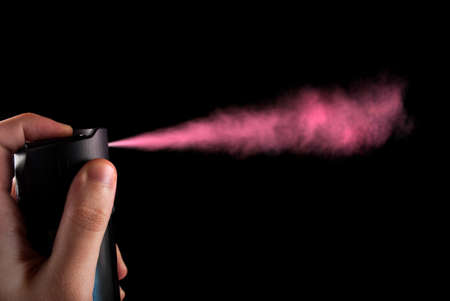 Pink aerosol cloud is out of spray bottle in hand, close upの写真素材