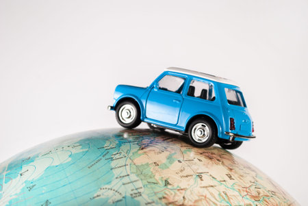 NIS, SERBIA - JANUARY 8 2018 Miniature figure toy car Mini Morris on geographical globe of earth on white background in studio. Travel concept.のeditorial素材