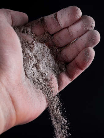 Gray ash pour out of human hand isolated on black. Close up. Selective focusの写真素材