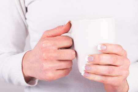 Coffee cup in beautiful girl hands with french nails polish. Close upの写真素材