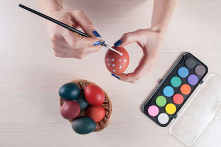 Young woman painting Easter eggs with brush. Top view, close upの写真素材