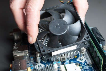 NIS, SERBIA - MARCH 10 2018: Applying cooler on computer CPU with hand on motherboard. Close up, selective focusのeditorial素材