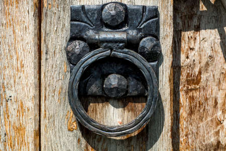 Old metal door knocker in circle shape on wooden door. Close upの写真素材