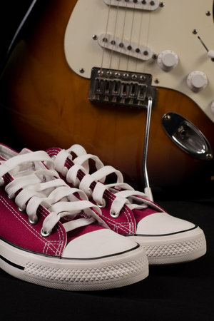Retro Red sneakers and blurred guitar in background. Close up, selective focus. Rock and Roll...