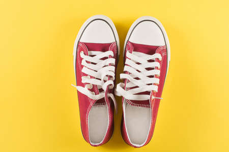 New red sneakers on yellow background with copy space. Top view. Retro fashion conceptの写真素材