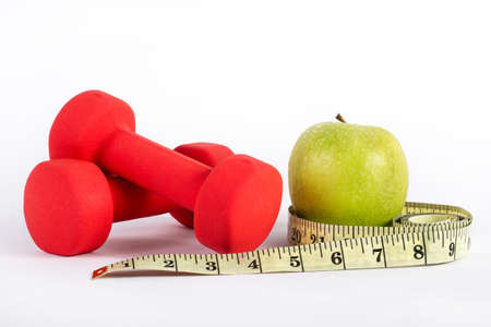 Red dumbbell fitness, measuring tape and green apple isolated on white background. Health, diet and sport conceptの写真素材