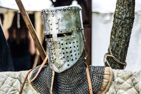 Medieval old knight helmet and chain mail for protection in battle. Very heavy headdress on stand in nature. Middle ages armor conceptの写真素材