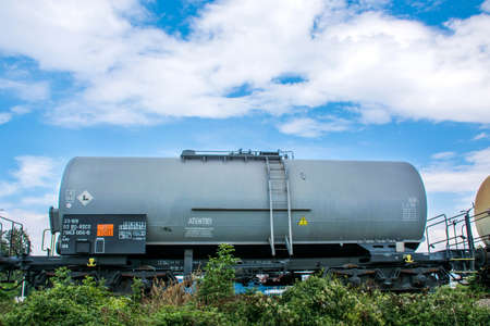 Nis, Serbia - July 08, 2018 Tanks cargo with gas or oil transportation by railroad in nature and blue cloudy sky. Fuel in gray wagon on railwayのeditorial素材