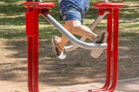 Woman legs on exercise equipment in public park. Fitness and gym concept. Close up, selective focus