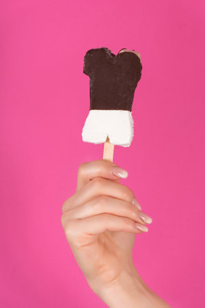 Young girl hand holding popsicle isolated on pink background in studio. Summer ice cram concept....