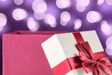 Red opened gift box with bow and purple background with bokeh. Christmas and holiday present concept. Close up, selective focusの写真素材