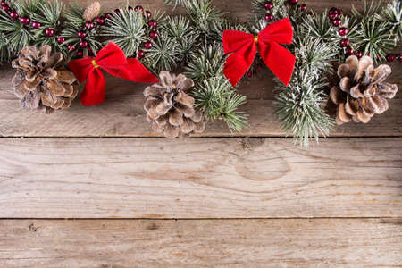 Christmas and New year holiday background with fir tree and pine cone with snow and red bow on wooden retro background. Space for text and design. Close up, selective focusの写真素材
