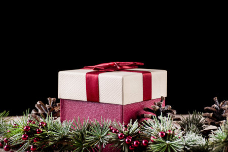 Gift box with red bow and fir tree with pine cone, black background. Christmas and New Year holiday concept. Close up, selective focusの写真素材