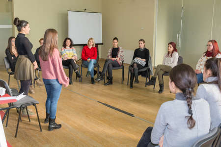 Nis, Serbia - February 13, 2019: Two teachers and group of young students having a group discussion in the big classroom and sitting in a circle on chairsのeditorial素材