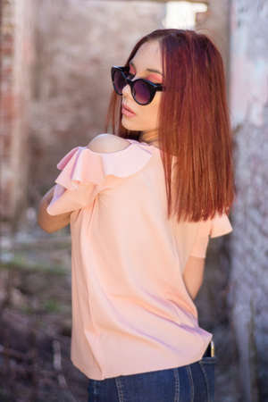 Beautiful young redheads woman with sunglasses portrait in old retro ruin house with red wall bricks. People rest and lifestyle concept. Close up, selective focusの写真素材