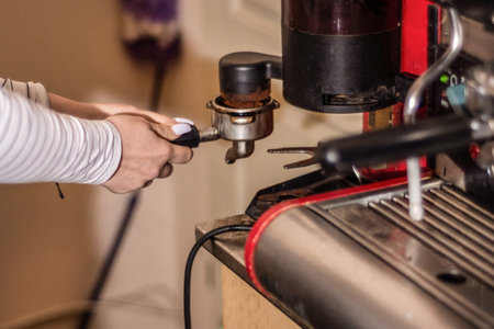 Girl making espresso coffee on a professional machine in the bar. Girl hand mill coffee, the process...