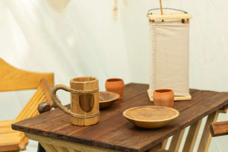 Medieval wooden beer mug and plates on the wooden desk. Very old wooden dishes and bowls for water or alcohol drink and food. Close up, selective focusの写真素材