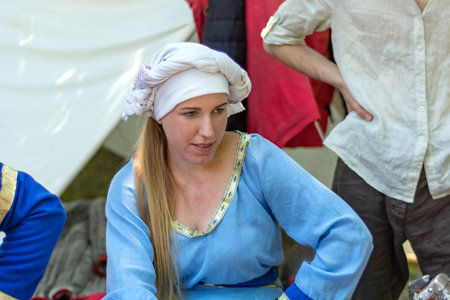 Nis, Serbia - June 15. 2019: Portrait of a medieval girl in a blue traditional dress and a white cap...