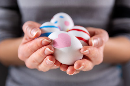 Female hands with Easter colorful eggs. Girl holding group of painting eggs in hands indoor. Easter...
