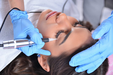 Permanent makeup eyeliner procedure, applying on a beautiful young girl in a beauty studio with a...