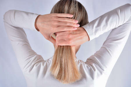 Young girl with blonde shaggy hair change hairstyles with hands. Attractive skinny girl isolated on studio white. Cares about healthy and clean hair. Close up, selective focusの写真素材